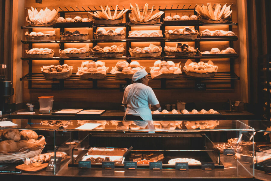 Bäckereifachverkäuferin vor Regal mit Broten in Bäckerei