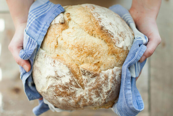 Brot in Geschirrtuch wird von zwei Hängen übergeben