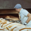 Bäcker backt Brot vor Backofen