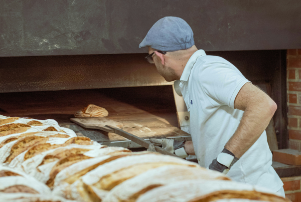 Bäcker backt Brot vor Backofen