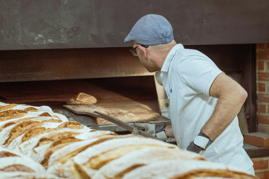 Bäcker backt Brot vor Backofen